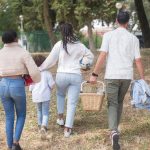Family walking together carrying picnic basket in a sunny park.